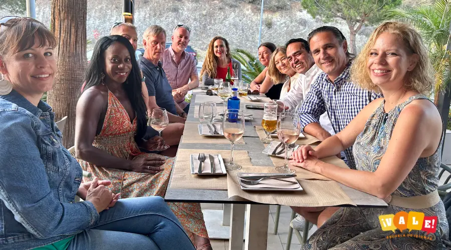 Grupo de alumnos adultos conversando en una terraza, demostrando que el mejor método para aprender inglés es practicar el idioma en situaciones reales y divertidas.